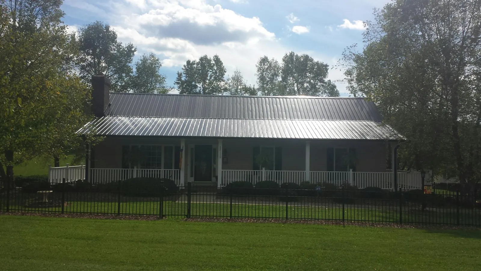 Gray metal roof on a brick ranch with a full width front porch — Gutter Guard Installation work by our crew in Bessemer