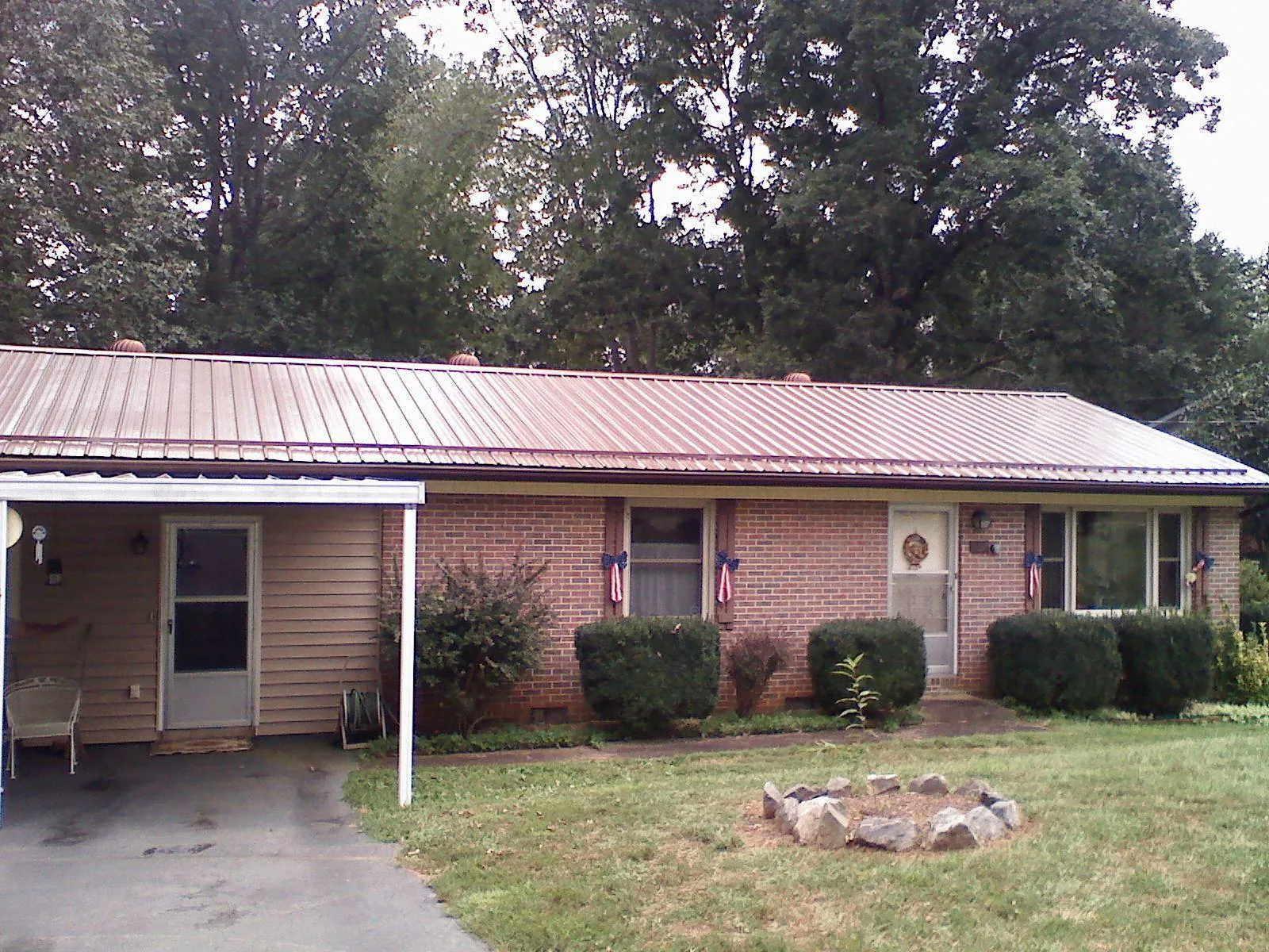 Bronze metal roof and carport on a brick ranch home — Roof Repair work by our crew in Bessemer