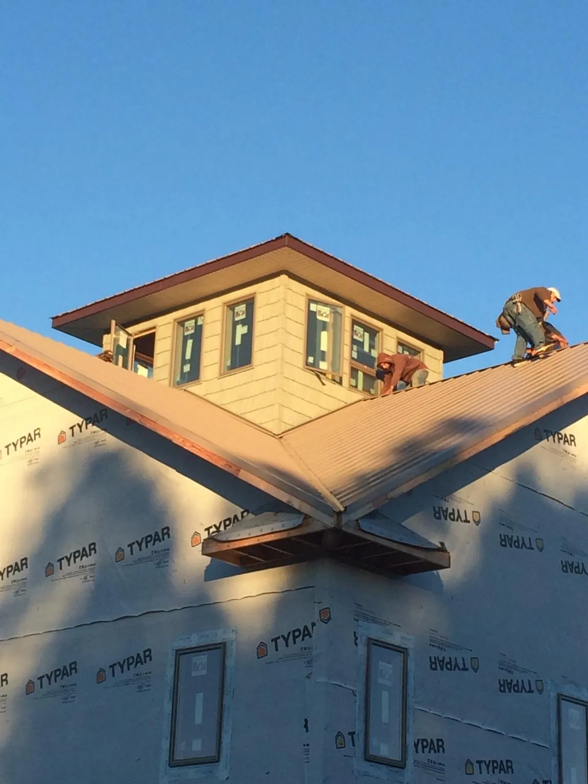Roofers working around a rooftop cupola on a new metal roof at sunset — Roof Waterproofing in Bessemer by Roofing Brothers